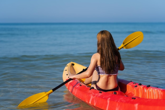 Mujer en traje de baño remando en un kayak en el mar