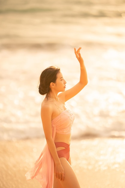 Mujer en traje de baño sexy posando en la playa tropical a la luz del atardecer