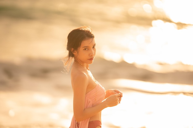 Mujer en traje de baño sexy posando en la playa tropical a la luz del atardecer