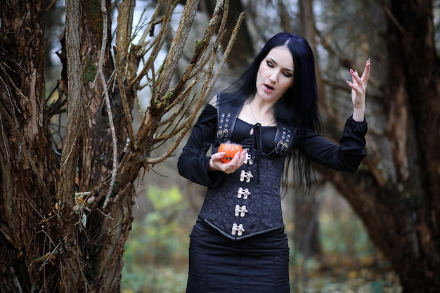 Una mujer con traje de bruja en un bosque.