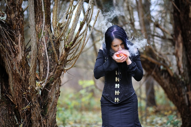 Una mujer con un traje de bruja en un denso bosque en un ritual