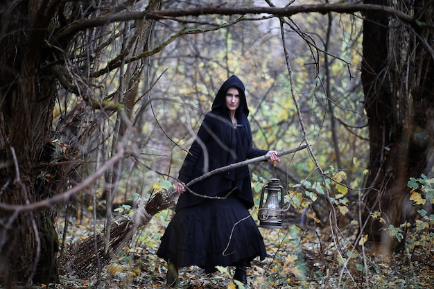 Una mujer con un traje de bruja en un denso bosque en un ritual