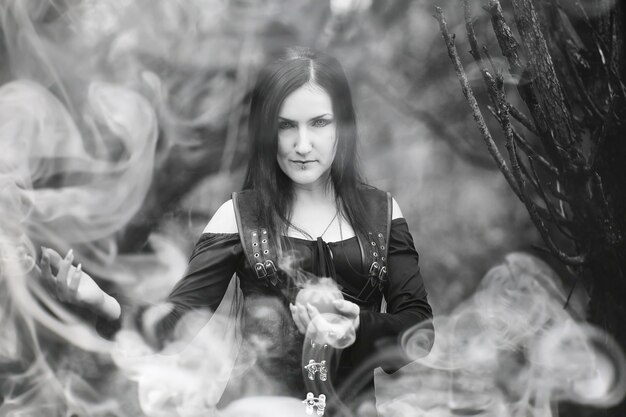Una mujer con un traje de bruja en un denso bosque en un ritual