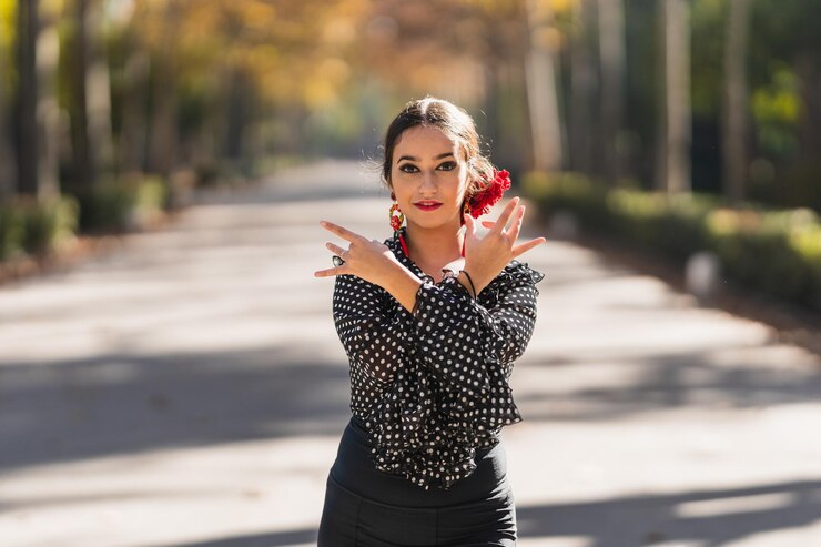 Mujer en traje de flamenca bailando frente a la cámara en un parque en un día soleado