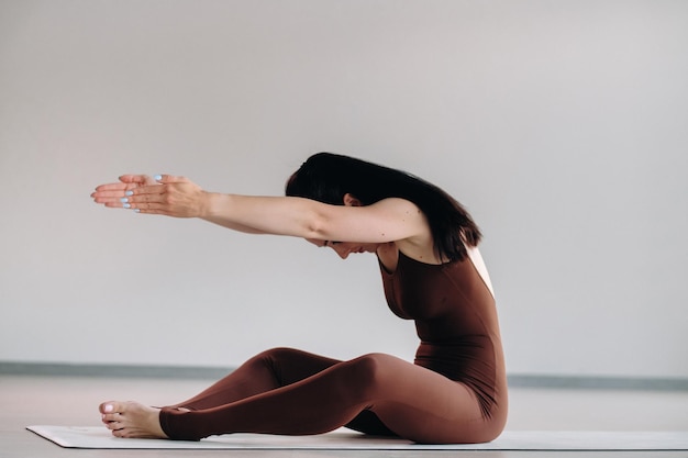 Una mujer con traje marrón hace yoga en una sala de fitness Estilo de vida saludable entrenamiento físico cuidado personal