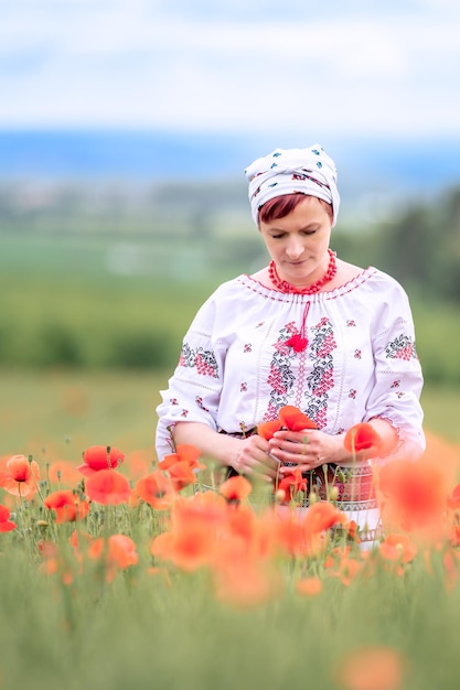 Mujer con traje nacional ucraniano en un campo de amapolas en flor