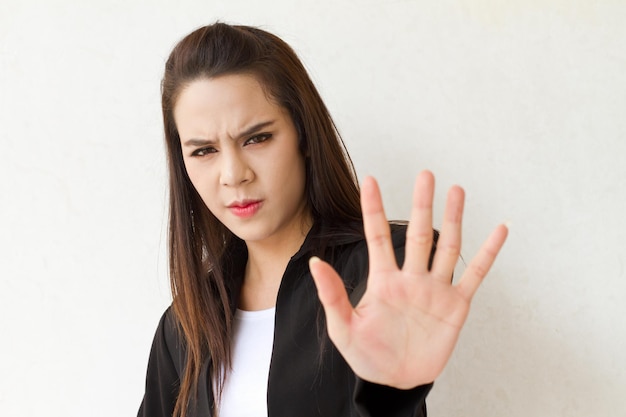 Mujer en traje de negocios que muestra el gesto de detener la mano con expresión facial seria y espacio de texto