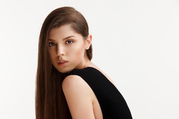 Foto mujer en un traje negro posando en un estudio.