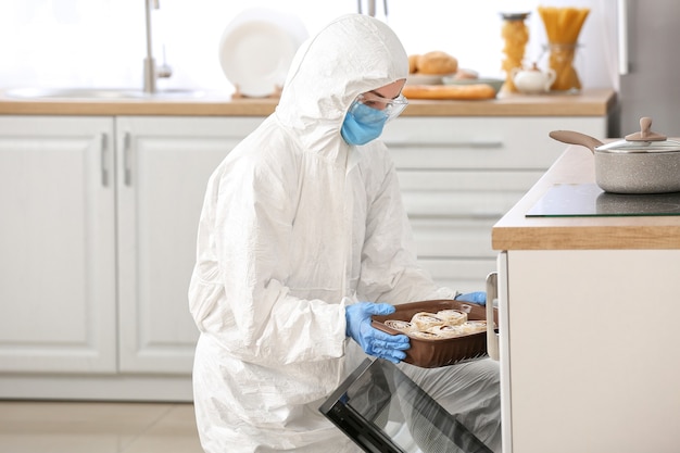 Mujer en traje de riesgo biológico cocinar en la cocina