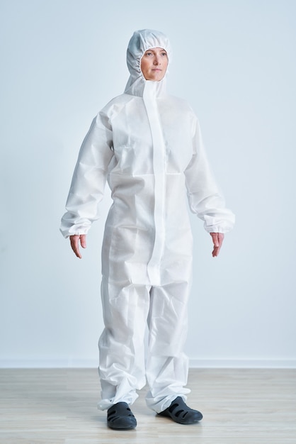 Foto mujer en traje de riesgo biológico sobre fondo blanco.