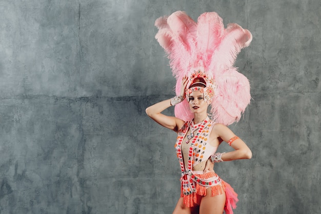 Mujer en traje de samba o lambada con plumaje de plumas rosas.