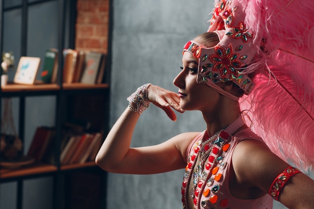 Mujer en traje de samba o lambada con plumaje de plumas rosas.