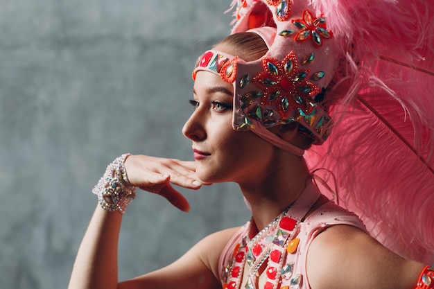 Mujer en traje de samba o lambada con plumaje de plumas rosas.