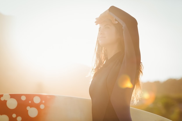 Foto mujer en traje con una tabla de surf en un día soleado