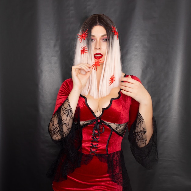 Mujer en traje de vampiro con muchas arañas rojas en el pelo