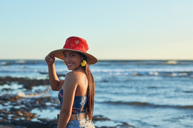 mujer en traje de verano mirando a la cámara con el mar