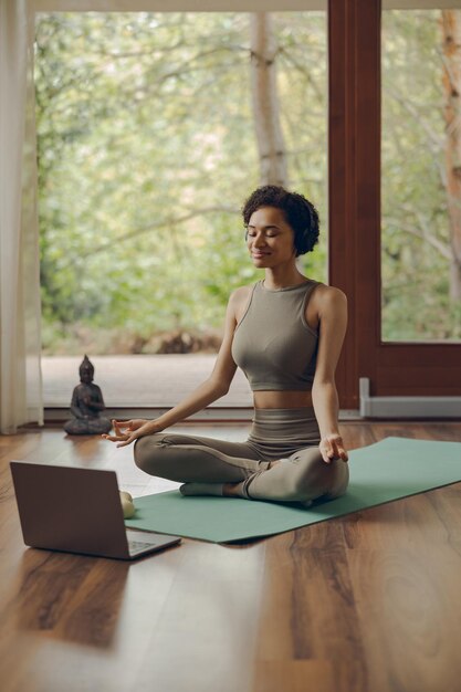 Mujer tranquila con auriculares meditando en la postura del loto en casa sentada en la alfombra concepto de meditación consciente
