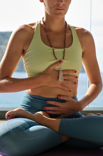 Mujer tranquila e irreconocible sentada en la postura del loto y respirando mientras medita durante la práctica de yoga en la terraza en un día soleado