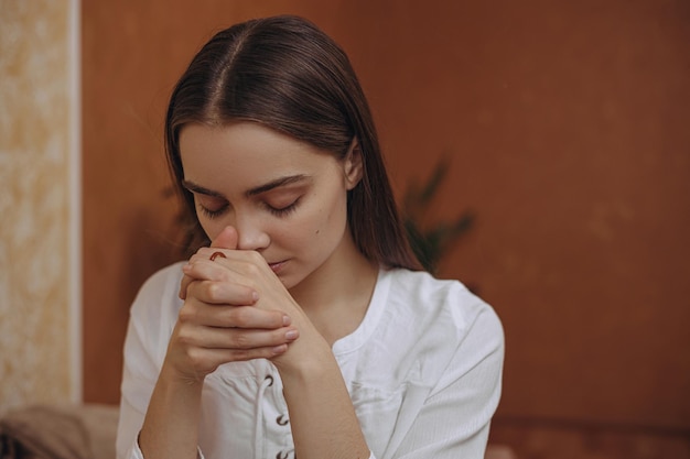 Mujer tranquila con los ojos cerrados oliendo aceite esencial aromático mientras hace aromaterapia en casa