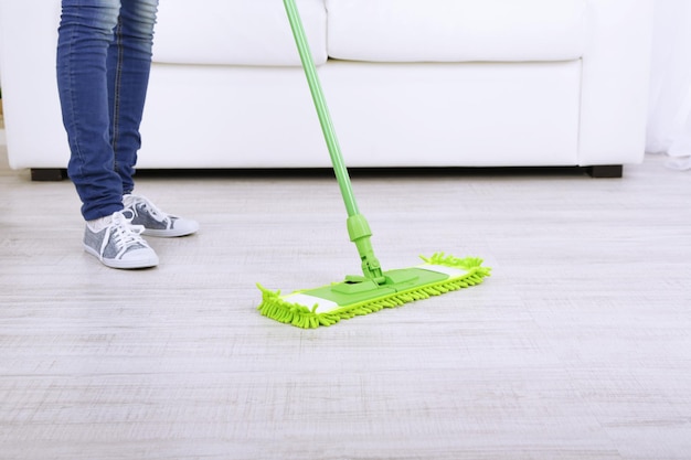 Mujer con trapeador limpiando piso de madera del polvo