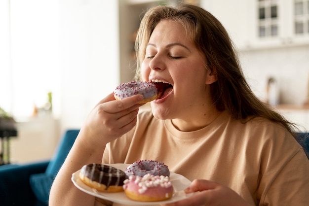 Foto mujer con trastorno alimentario tratando de comer donas