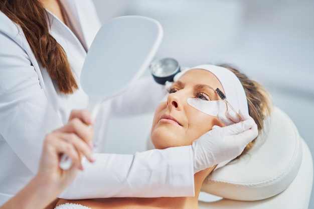 Mujer con tratamiento de cejas de cosmetología en salón de belleza