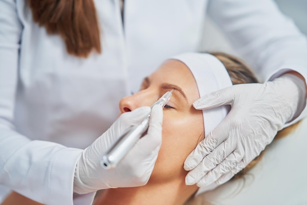 Mujer con tratamiento de cosmetología de cejas permanentes en el salón