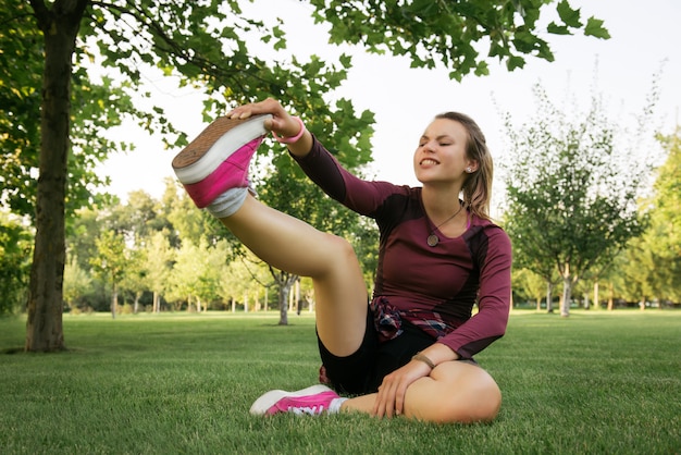 Mujer tratando de estirar al aire libre