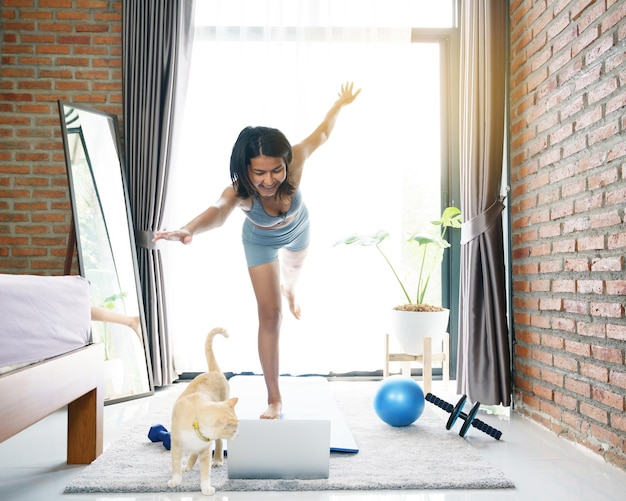 Foto mujer tratando de hacer ejercicio y mirando su computadora portátil