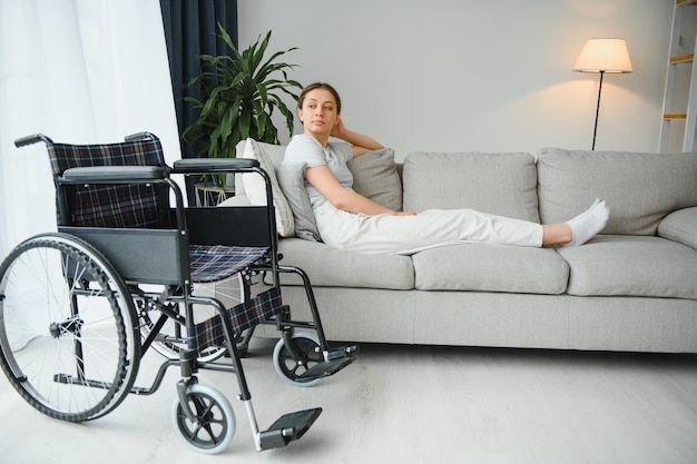 Mujer tratando de sentarse en silla de ruedas desde el sofá