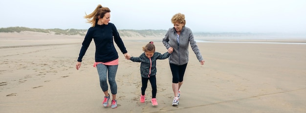 Mujer de tres generaciones corriendo en la playa en otoño