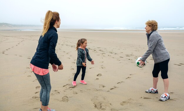 Mujer de tres generaciones jugando en la playa en otoño