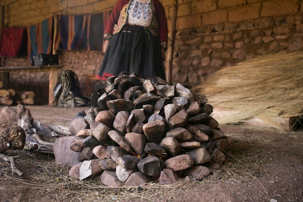 Mujer de una tribu quechua preparando horno de piedra para la ceremonia de la Pachamanca en Maras, Cusco, Perú.