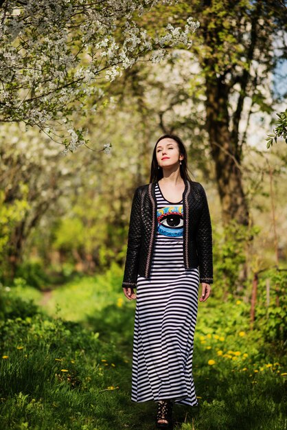 La mujer triguena en la chaqueta de cuero presentó en jardín de la primavera.