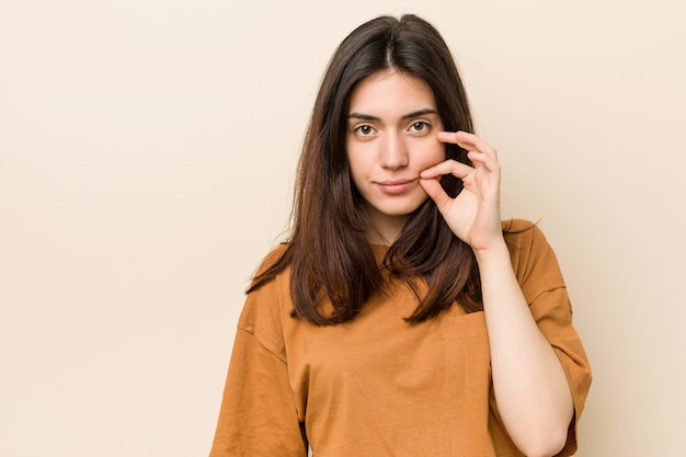 Mujer triguena joven con los dedos en los labios que guardan un secreto.