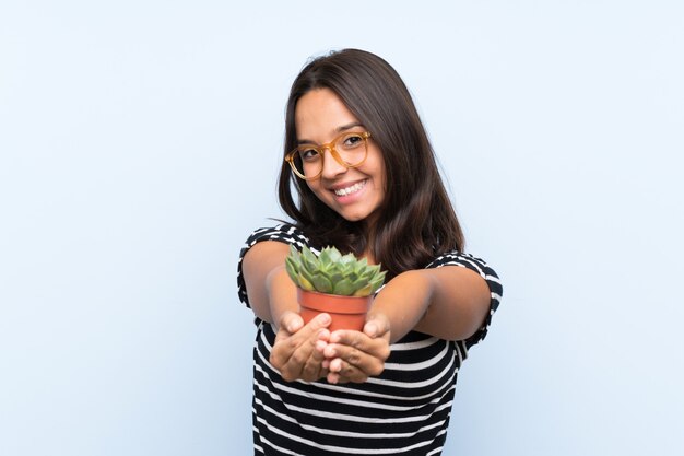 Mujer triguena joven que sostiene una planta