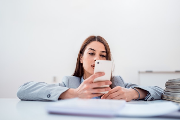 Mujer triguena joven que usa el teléfono en sitio brillante.