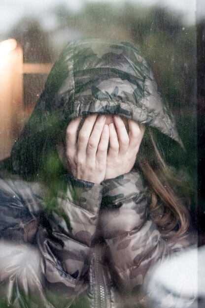 Foto mujer triste al lado de la ventana