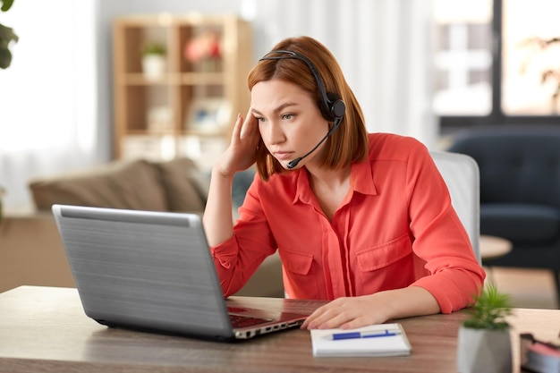 mujer triste con auriculares y portátil trabajando en casa