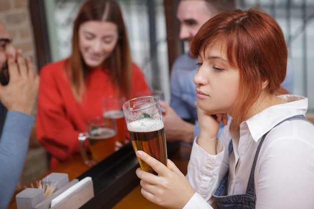 Mujer triste bebiendo cerveza en el pub