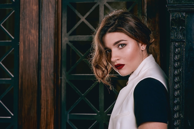 Mujer triste con cabello castaño corto con elegante maquillaje en vestido negro y chaleco blanco