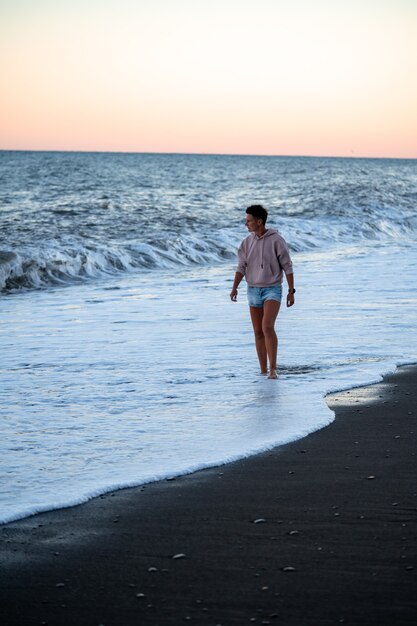 Mujer triste camina por la playa con espectaculares olas frías