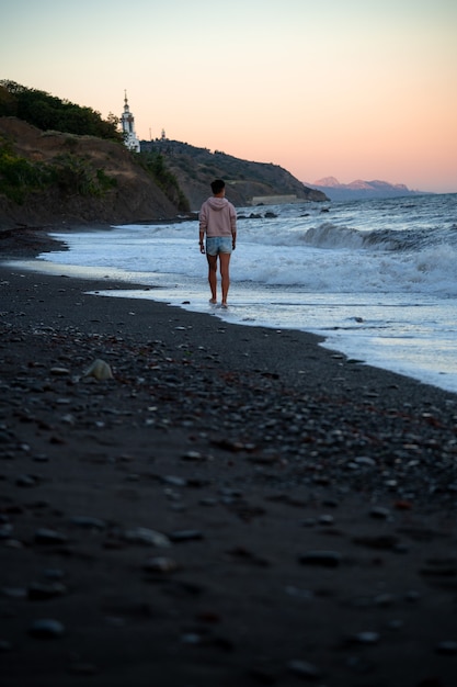 Foto mujer triste camina por la playa con espectaculares olas frías