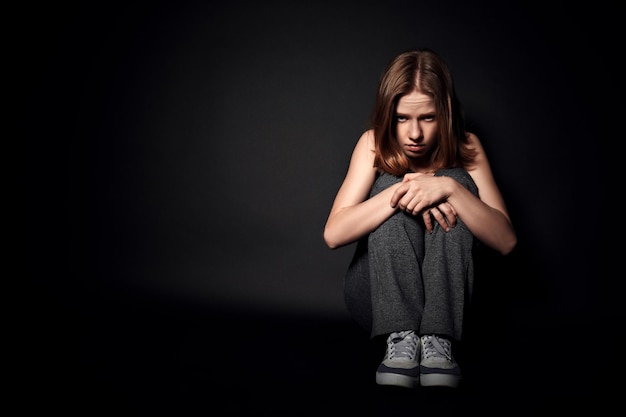 mujer triste en depresión y desesperación llorando sobre fondo negro oscuro