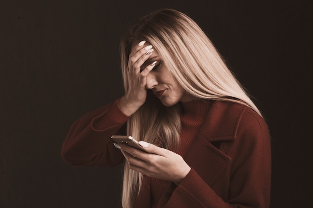 Mujer triste deprimida sosteniendo teléfono aislado