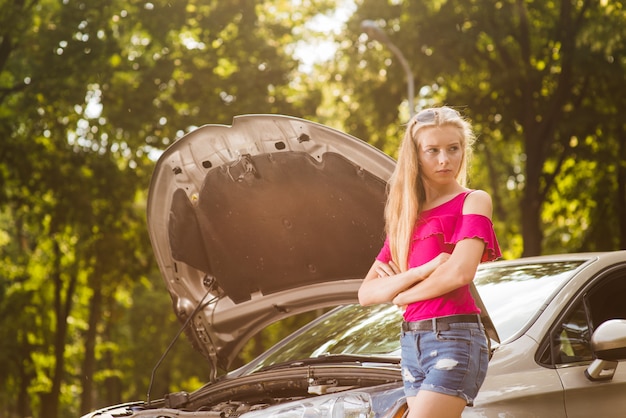 Mujer triste y enojada con auto roto