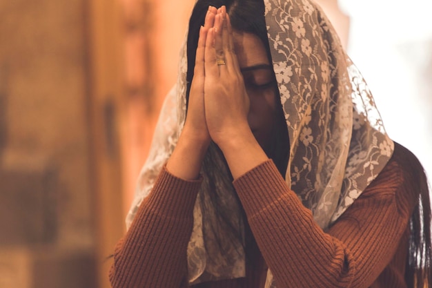 Mujer triste joven que ruega en iglesia