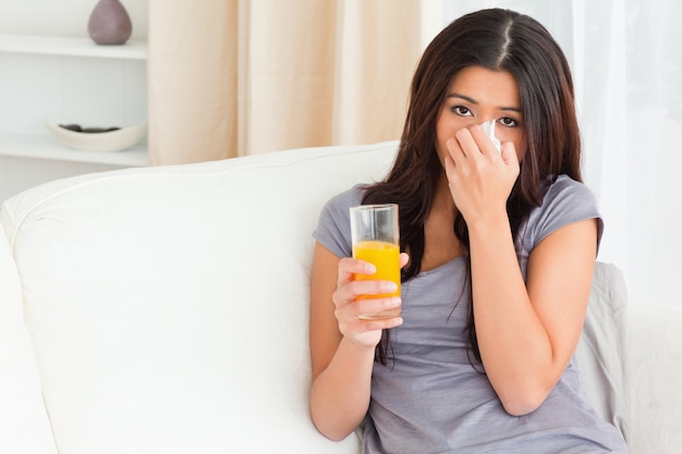 mujer triste con jugo de naranja y pañuelo