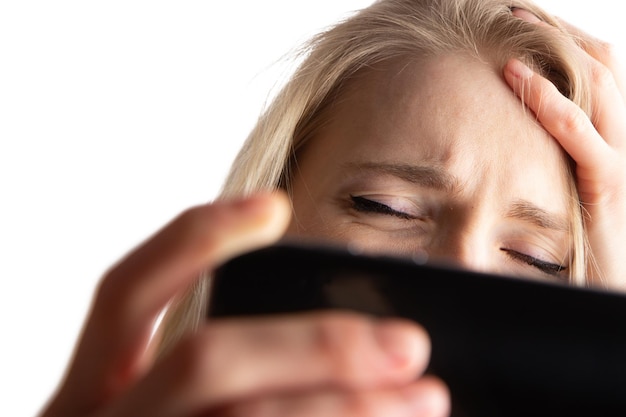 Mujer triste con la mano en el cabello usando teléfono inteligente contra un fondo blanco