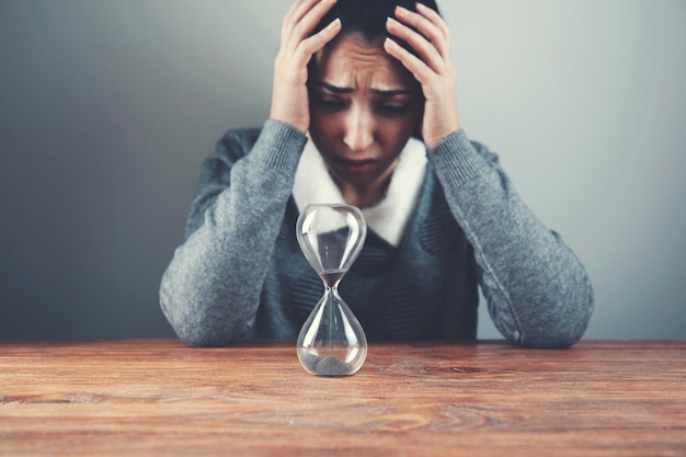 Mujer triste con la mano en la cabeza y el reloj